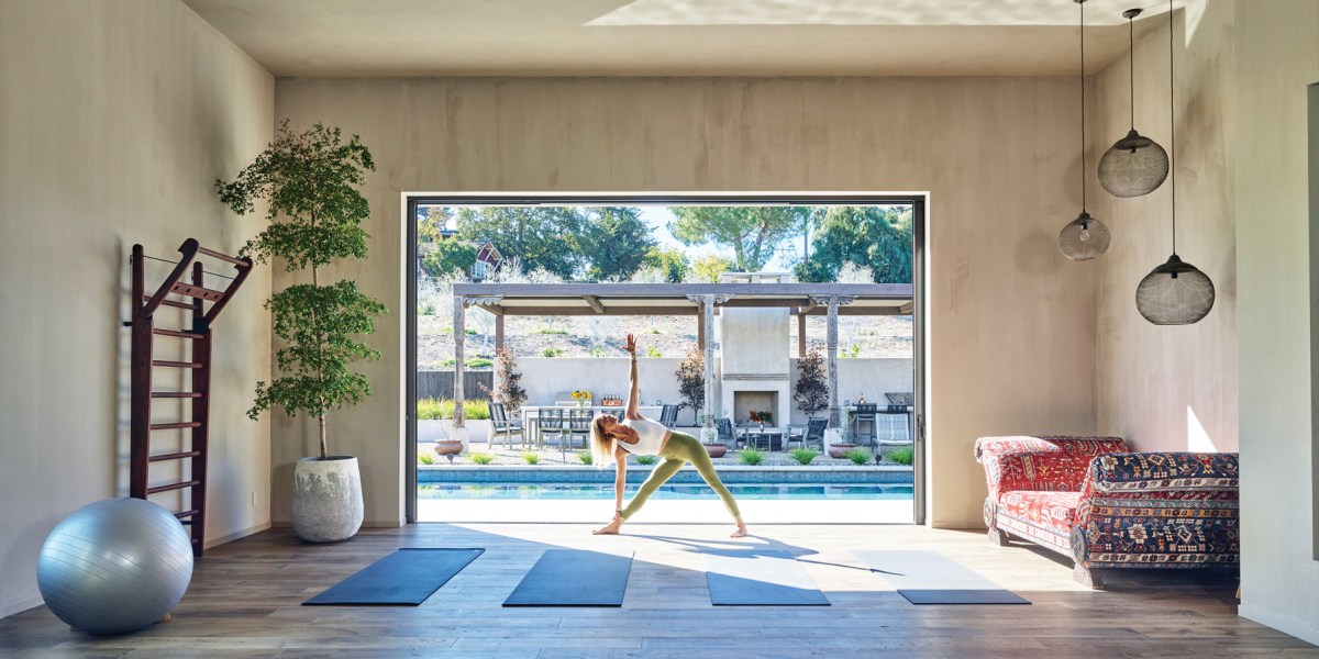 Woman in a yoga pose in a room overlooking a pool