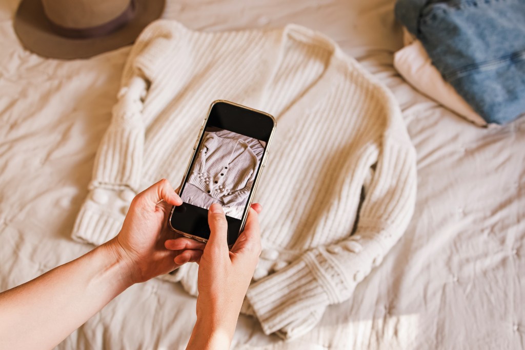 Woman taking photo of a sweater with her phone