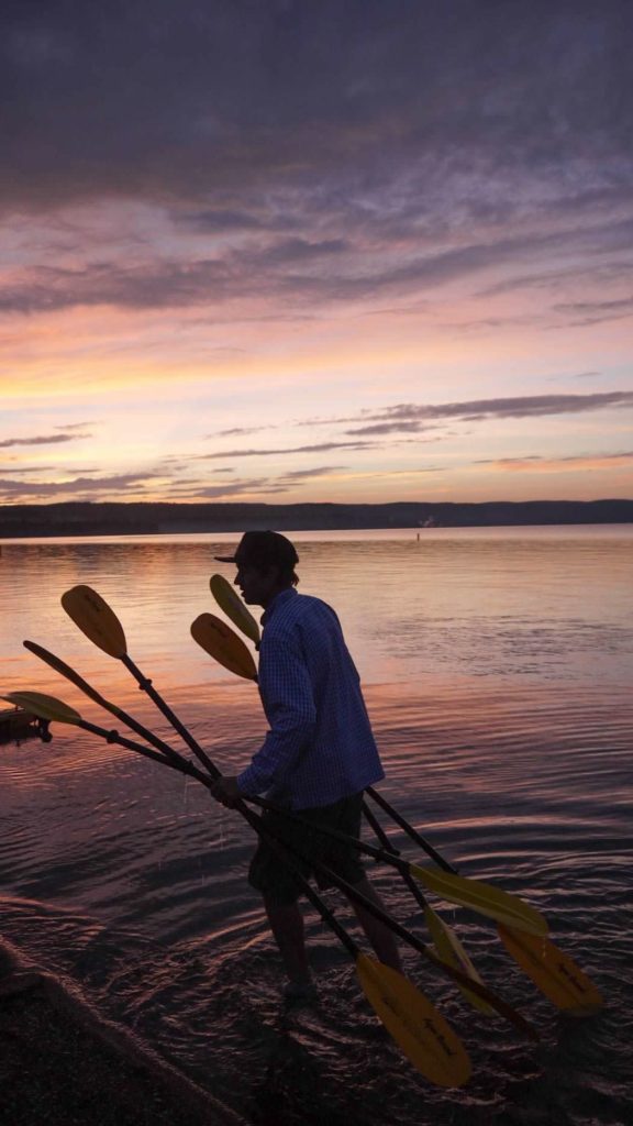 guide holding paddles lake sunset Yellowstone