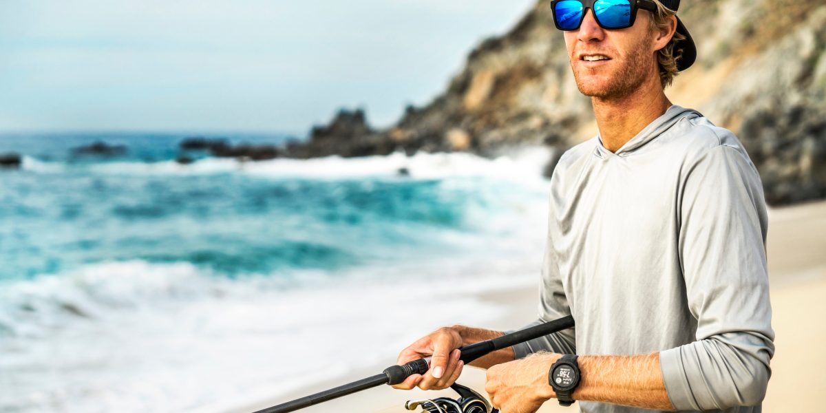 man standing on beach with fishing rod