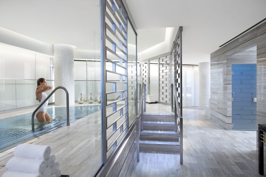 A woman in an indoor pool area at a spa.