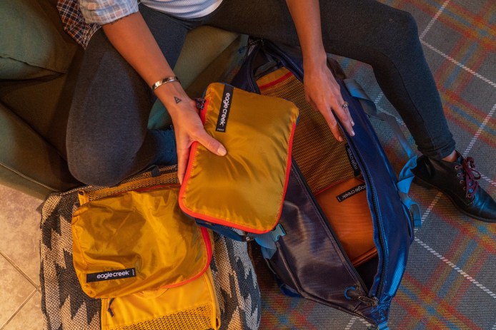person packing small containers into larger bag