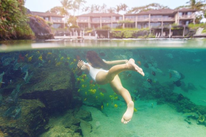 Girl swimming in ocean with fish
