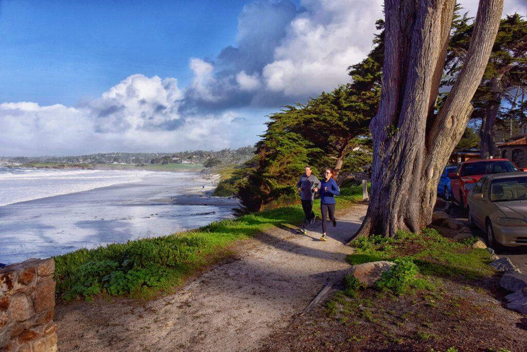Two people running on a path near the ocean.