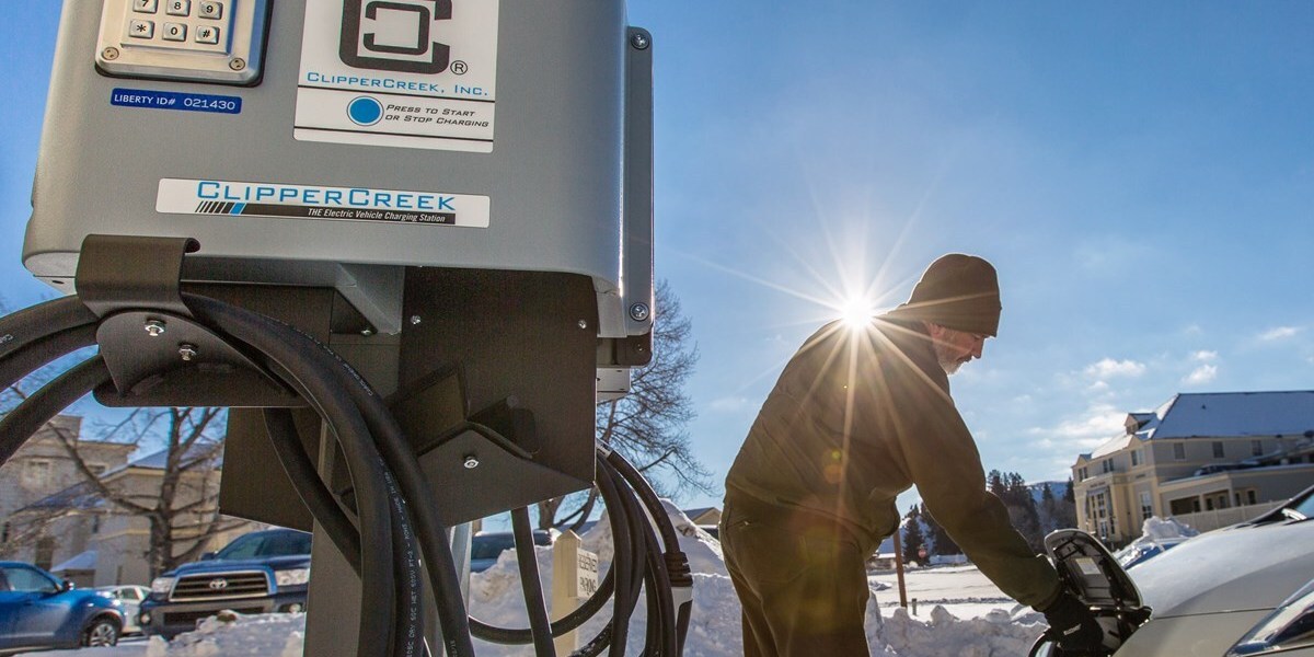 a man places a plug into his electric car at a charging station