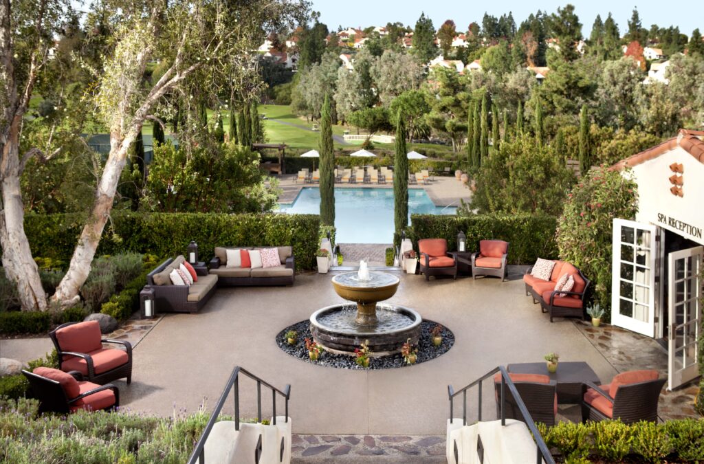 An outdoor terrace at a spa, overlooking a pool and landscaping.