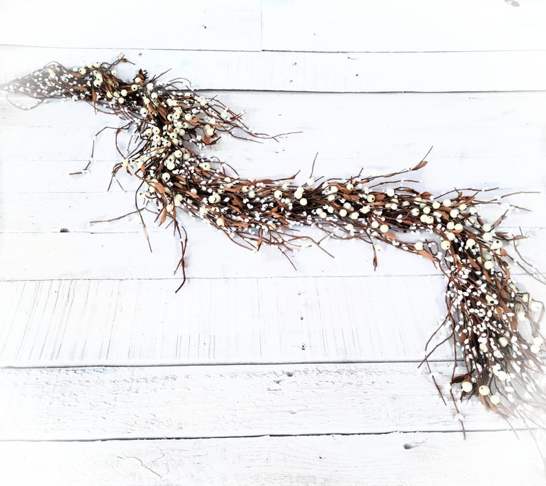 white and brown berry garland on white wooden floor