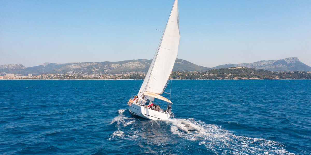 sale boat on the ocean with coastline in the background