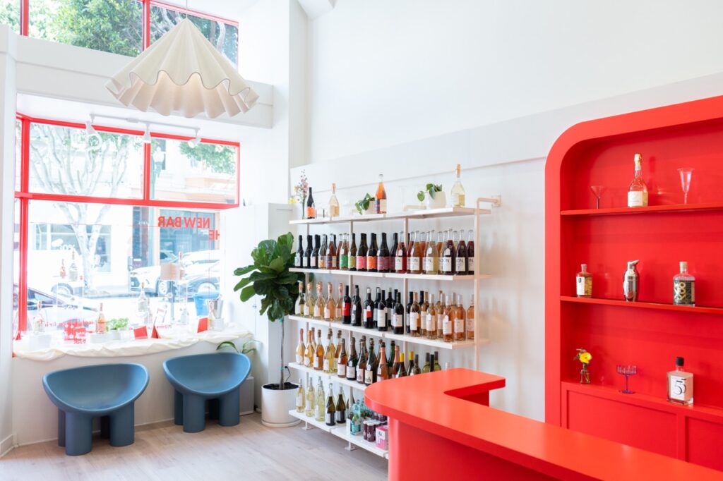 The inside of a colorful bar with several shelves with wine bottles.