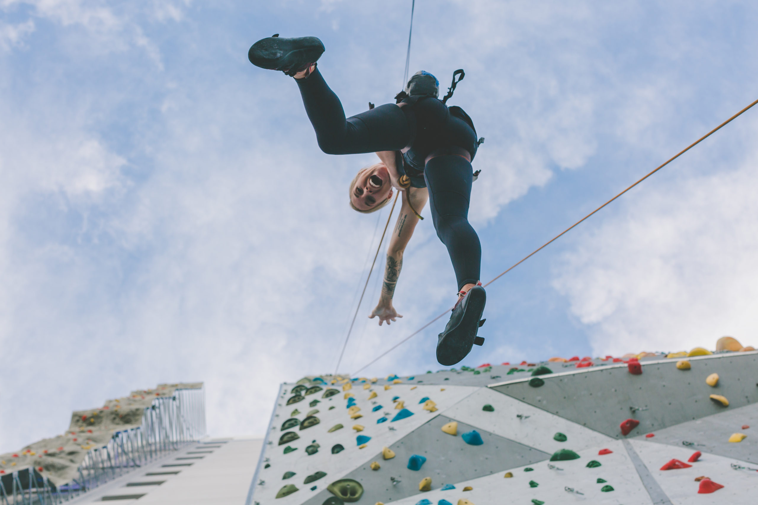 Climber hangs off rock wall.