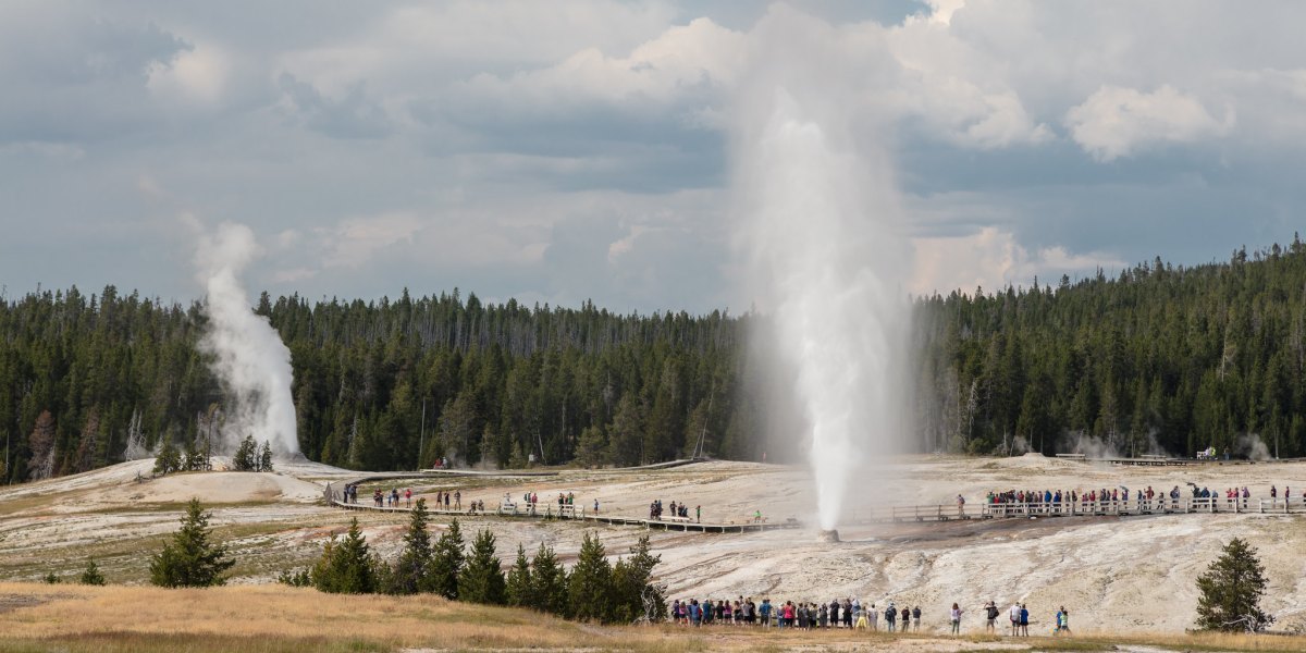 People watching Beehive Geyser erupt with Lion Geyser in Yellowstone off Highway 89