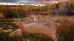Woman soaking in hot springs outside in fall at Dunton Hot Springs