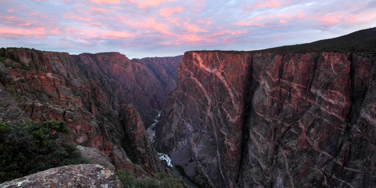 Sun rises over the Painted Wall cliff at Black Canyon of the Gunnison, Colorado, a great alternative to Grand Canyon, which is affected by overtourism