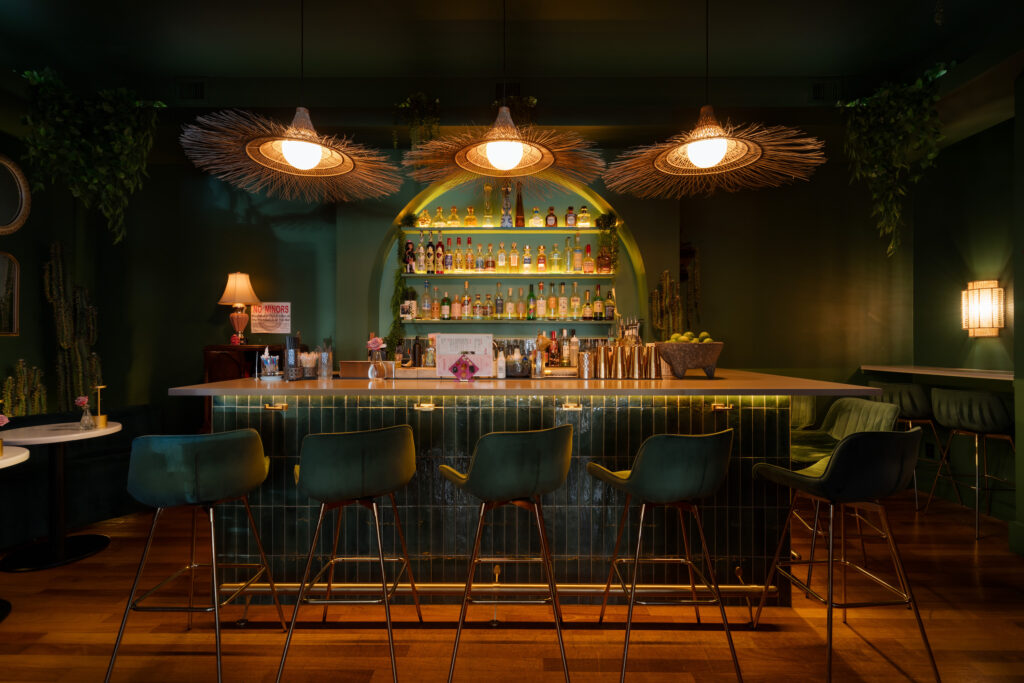 A dimly lit restaurant featuring a bar with dark green interiors.