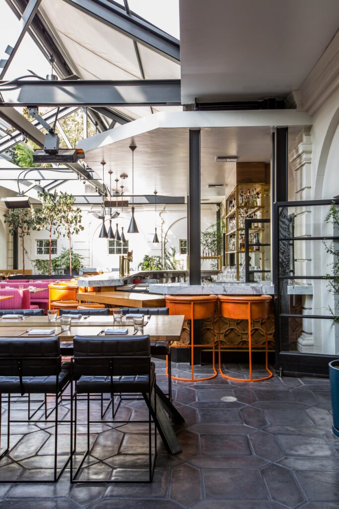 The interior of a restaurant with orange and pink furnishings and plants.