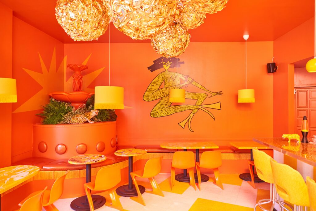 The dining room of a restaurant with orange and yellow interiors.