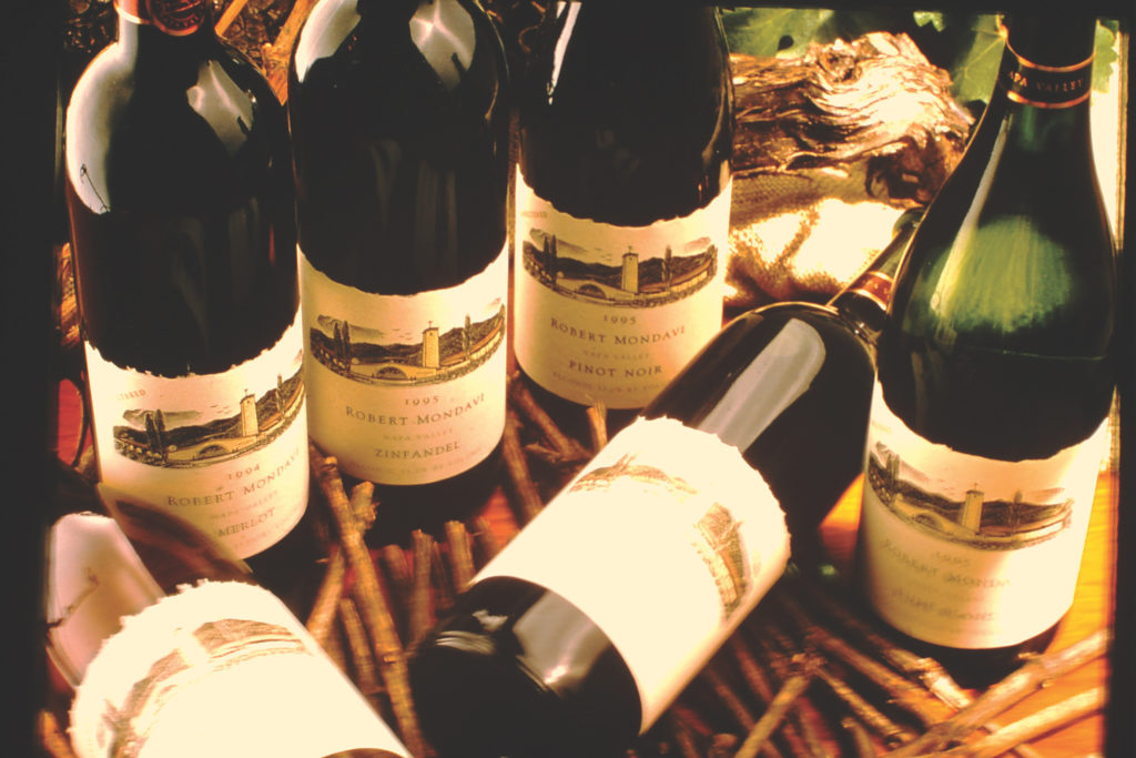 Six Robert Mondavi wine bottles with four upright and two displayed decoratively on their sides