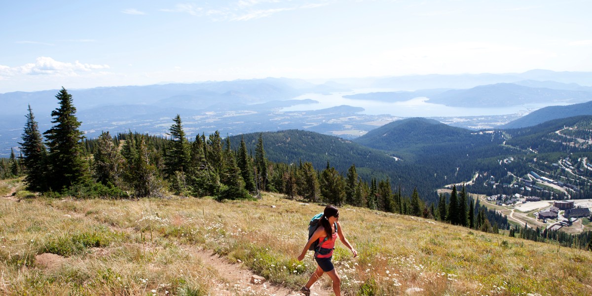 A woman hiking up Mt. Schweitzer while overlooking Sandpoint, Idaho, and Lake Pend Orielle.