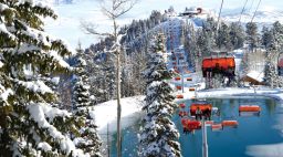 The ski gondolas at Park City Mountain surrounded by snowy slopes and trees during the day