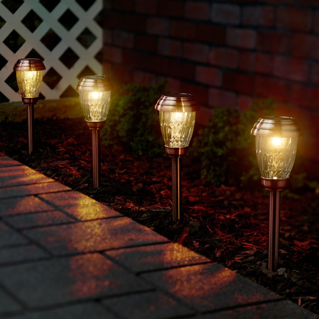 brass path lights in mulch by paved path