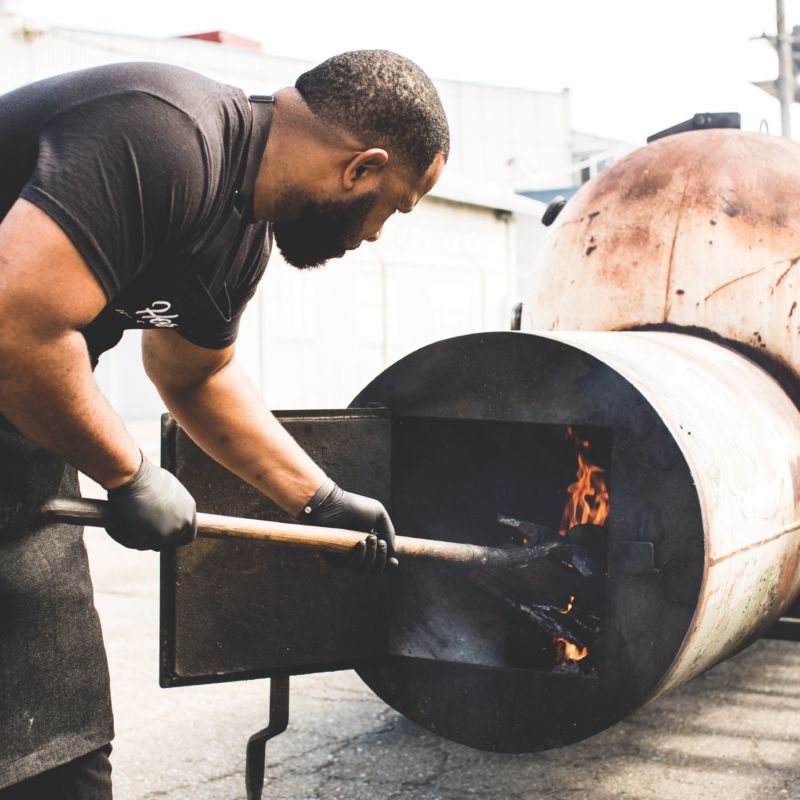 Matt Horn loading wood into fire of smoker