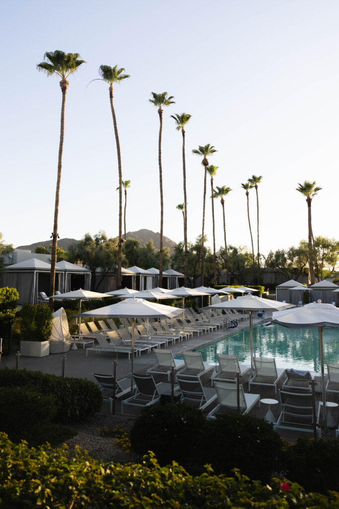A pool area with cabanas, lounge chairs, and umbrellas.