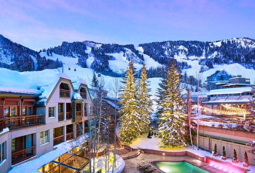 The Little Nell exterior covered in snow with trees in middle with lights and pool lit up