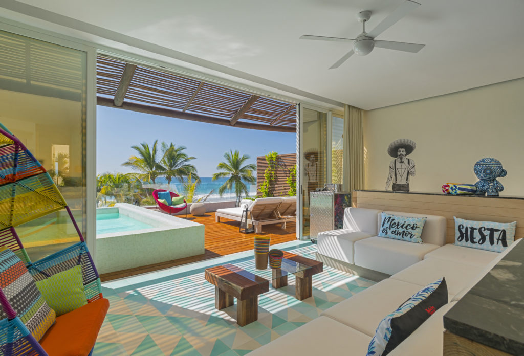 living room opens up to deck with hot tub and palm trees